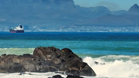 drone disparado de las ondas de tele golpeando las rocas en frente de big bay, ciudad del cabo