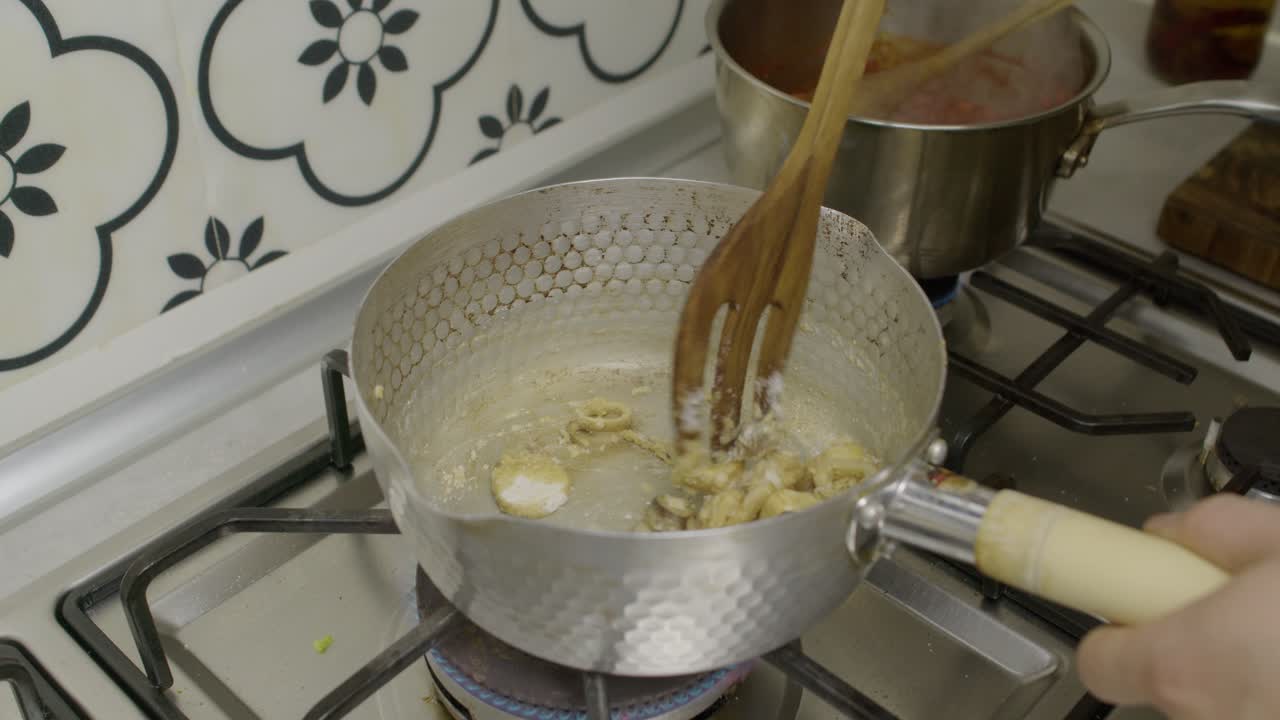 revolviendo los champiñones fritos en una olla en la estufa de gas