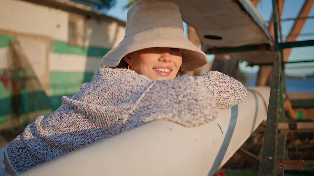 호수 근접에서 빛을 따뜻하게 하는 휴가 소녀. 모자 입고 포즈를 취하는 미소 짓는 모델