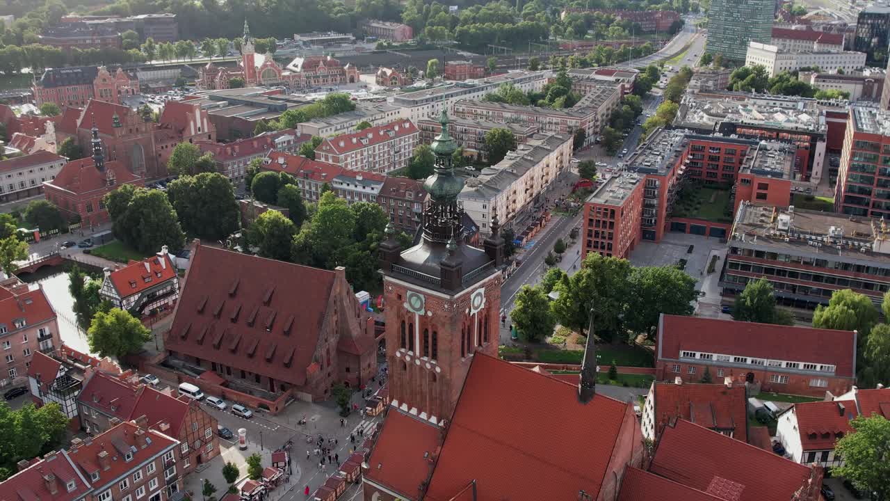 Drone mengorbit menara gereja menampilkan atap dan jalan-jalan kota tua Gdansk