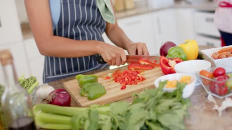 feliz mujer biracial con delantal y cocinando en la cocina en cámara lenta