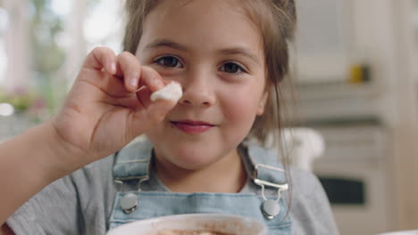 cute little girl eating cookie dipping biscuit into hot chocolate enjoying delicious treat at home in kitchen