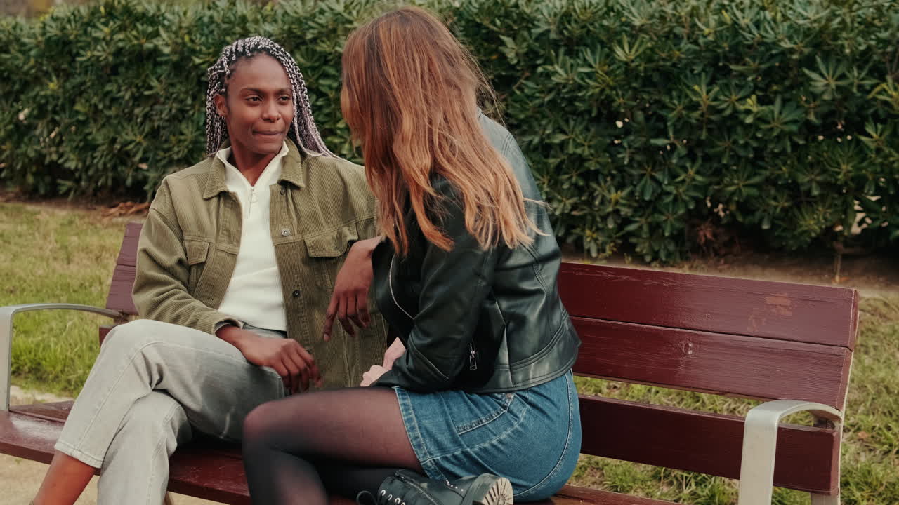 Two Diverse Young Women Having a Conversation on a Park Bench