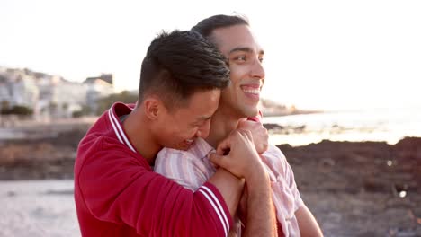 happy diverse gay male couple embracing at beach, slow motion