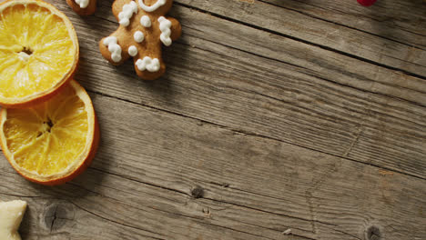 Video-of-biscuits,-oranges-and-red-fruits-over-wooden-background