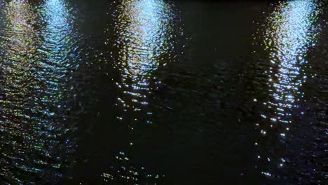 Shimmering-reflections-on-water-at-night,-with-colorful-light-patterns