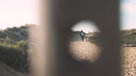 looking through hole in fencing young man walks off into the distance