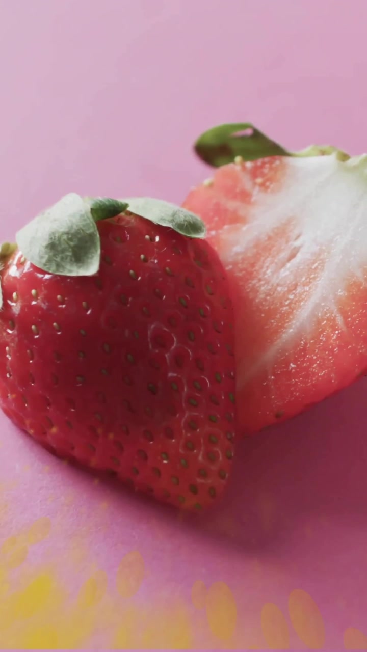 Composition of halved strawberries and spots of light over pink background