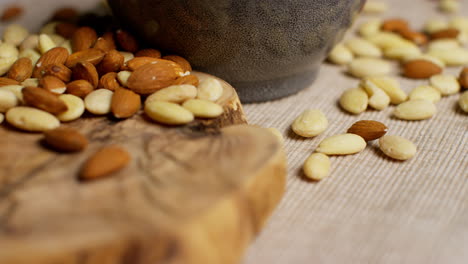 close up shot of raw and blanched almond nuts revolving next to bowl