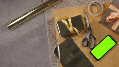 overhead shot of gift or present being wrapped on table at home with green screen mobile phone