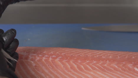 primer plano macro del chef quitando las espinas de un filete de salmón