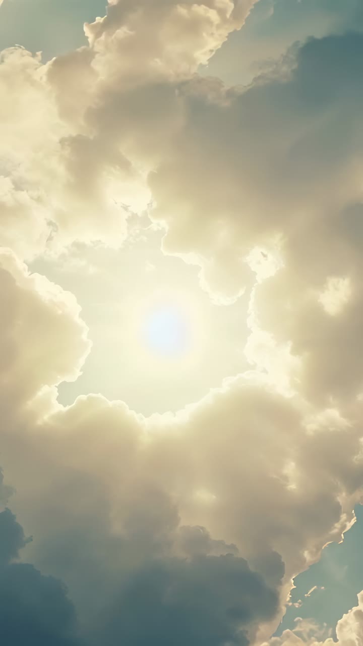 Vertical video: Shifting cloud mass opening bright sun at sky, rimlit edges, sunbeams and birds