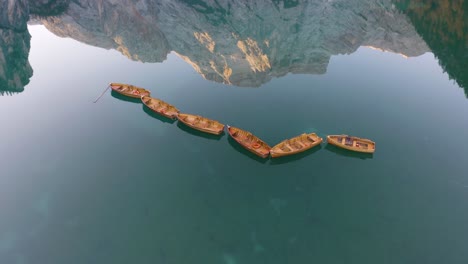 Vista-Aérea-Fija-De-Botes-De-Remos-De-Madera-En-Un-Hermoso-Lago,-Reflejo-De-Montaña