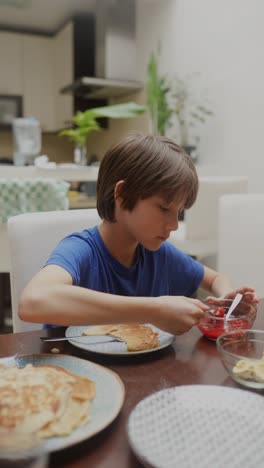 boy eating pancakes with strawberry jam