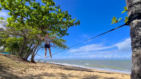 adult male getting on slackline and balancing at trinity beach in cairns