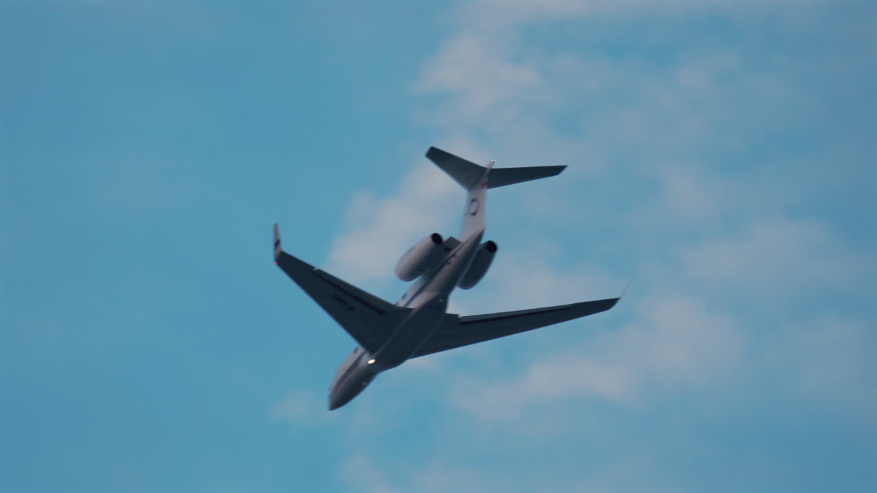 Cannes, France - October 9, 2025: A passenger jet soars high in the sky with light clouds in the background