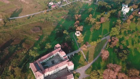 forward, tilt up high angle drone shot of a castle next to a village