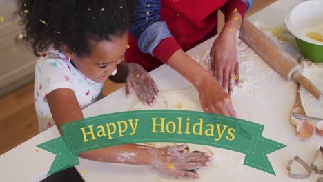 Animation-of-happy-holidays-over-happy-african-american-daughter-making-cookies-with-mother