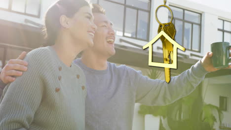 Animation-of-gold-house-key-and-key-fob-over-happy-biracial-couple-by-house