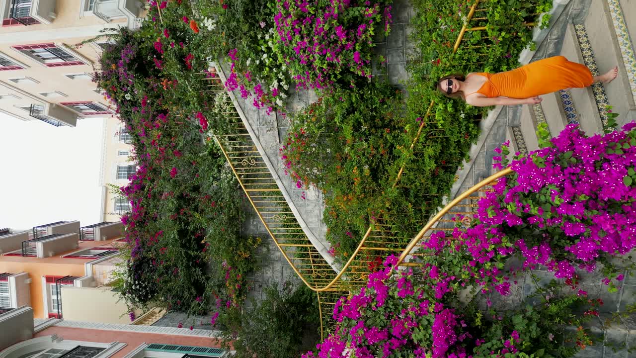 Vertical - Beautiful Woman Walking Down Thang Rong Stairs Through Colorful Flowers In Phu Quoc, Vietnam. high angle, tracking shot