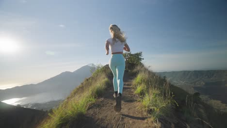 Mujer-Joven-Intrépida-Corriendo-En-El-Borde-De-La-Montaña-Del-Monte-Batur-Al-Amanecer