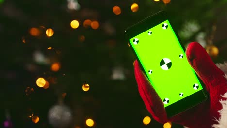 santa claus holding phone in hand. green chroma key for your ad.