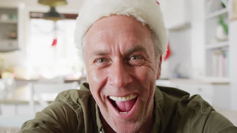 happy caucasian man wearing santa claus hat, having video call