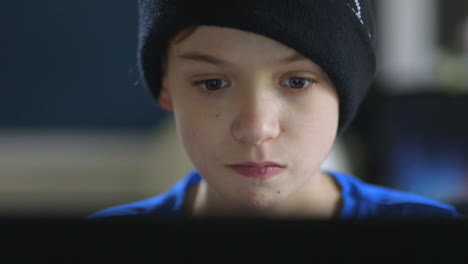 niño jugando juegos en su computadora portátil concentrándose en el primer plano de la cara