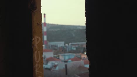 Derelict-building-window-view-of-factory-chimneys