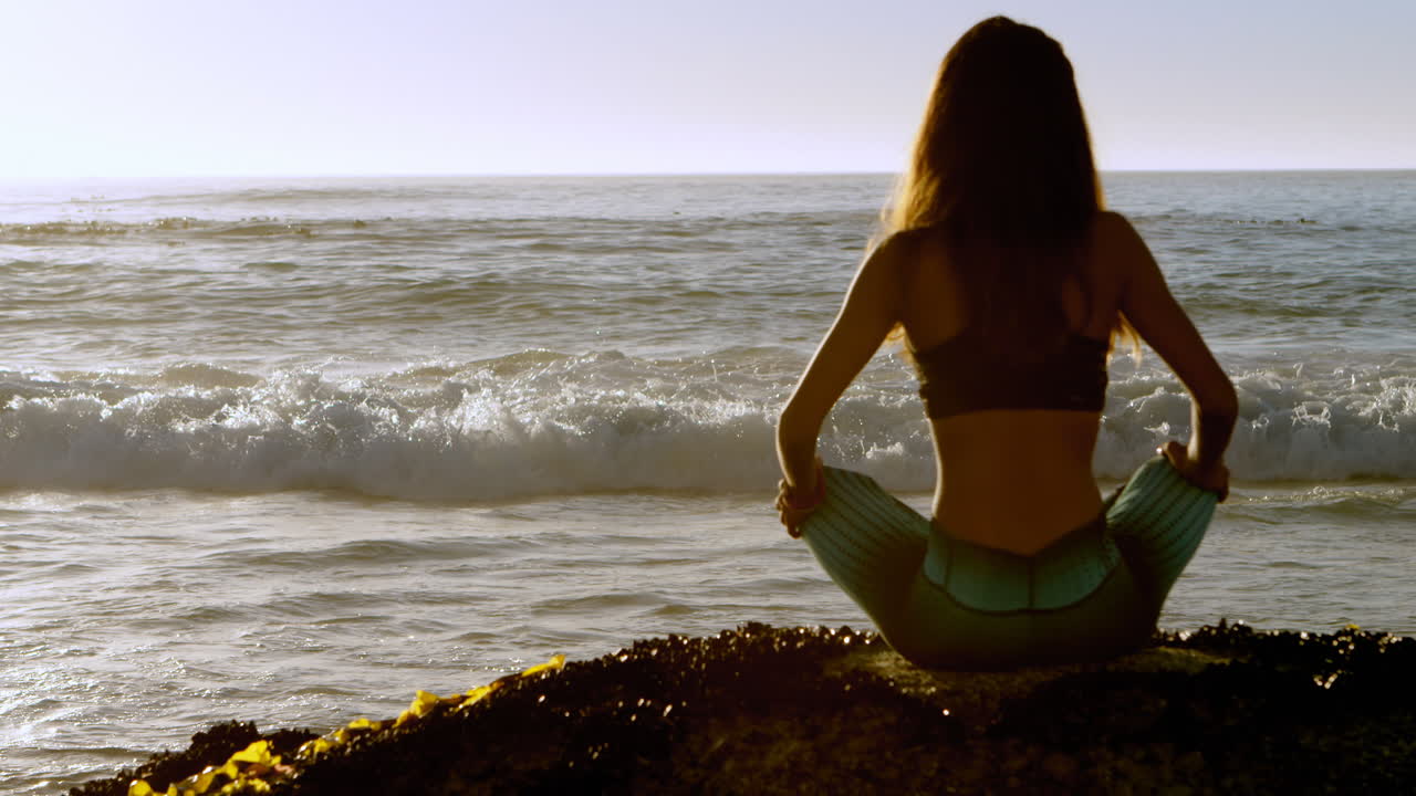 mujer en forma realizando yoga en la playa 4k
