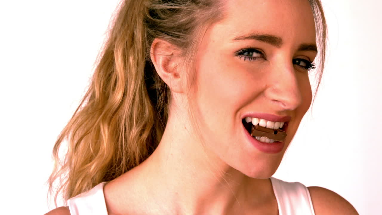 una bonita rubia comiendo una barra de chocolate