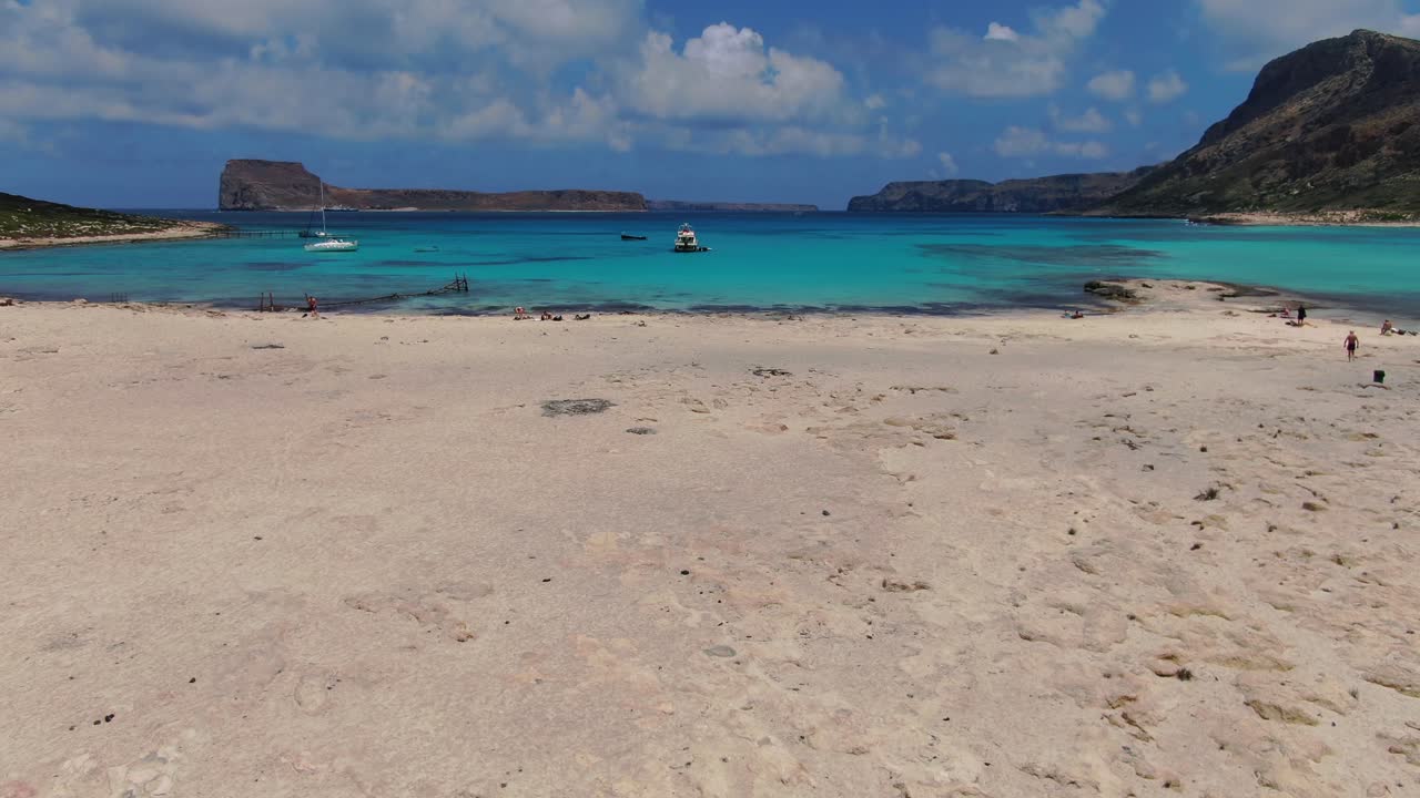 Balos Beach in Crete Greece with tourist transport ship on the blue water coastline, Aerial flyover reveal shot