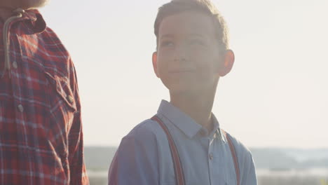 close-up view of teen nice boy walking with his grandpa and carrying equipment for fishing