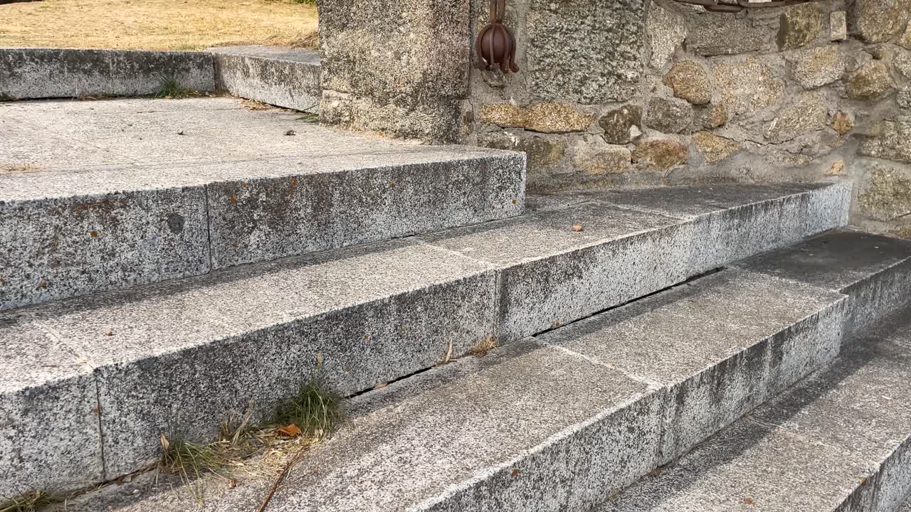 filming of stone stairs where you access a sanctuary, we see a stone block with a large iron chain serving as a handrail and another chain closing the entrance to the garden recreational area
