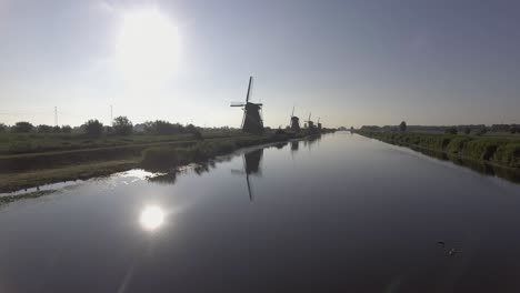 a drone shot panning forward, around dutch windmills during sunrise