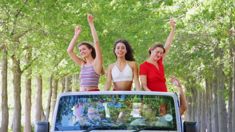 Girlfriends-standing-in-the-back-of-an-open-top-car-dancing