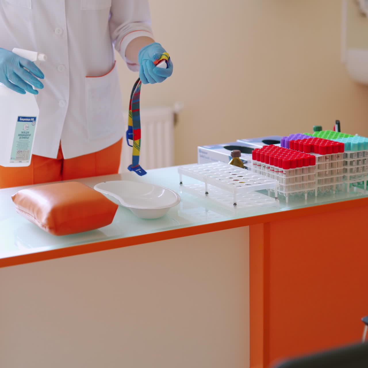 Young nurse in medical uniform. Beautiful woman assistant sterilizes medical instruments on the table with the spray. Healthcare concept.