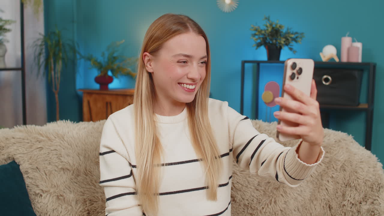 Caucasian woman smiling laughing talking during phone video call on sofa at home joyful emotions
