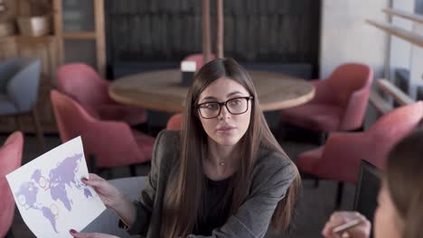 two attractive young women are sitting in a cafe