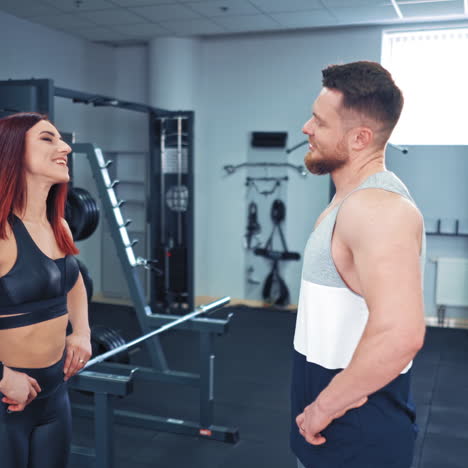 Smiling man and a woman in sportswear are training in fitness center. A happy couple standing one opposite another and doing neck exercises in the modern sports club.