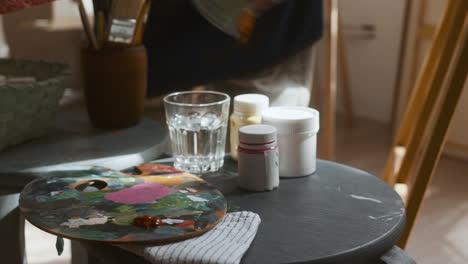 artist putting painting tools on a stool