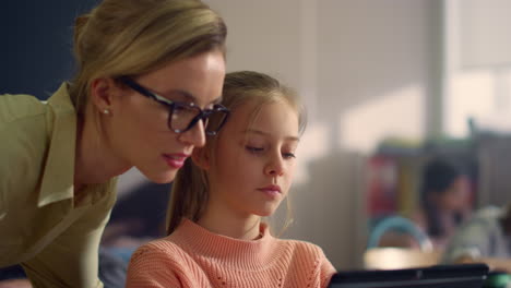 girl using digital tablet. teacher helping student to do class work on pad