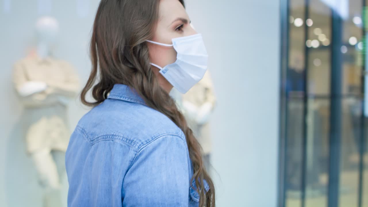 video de una mujer con máscara protectora caminando en un centro comercial