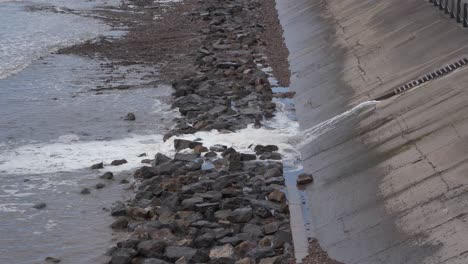 Water-being-released-from-the-artificial-beach-in-Weston-super-Mare-into-the-sea,-waves-crushing-into-the-rocky-beach