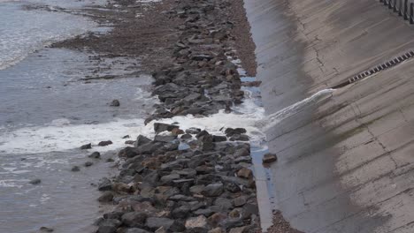 water being released from the artificial beach in weston-super-mare into the sea, waves crushing into the rocky beach