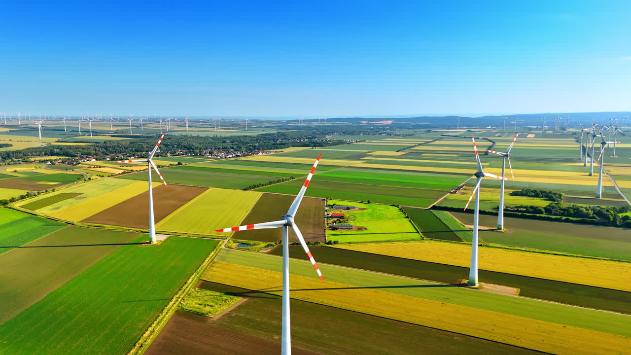 Wind turbines in the countryside. Several wind turbines stand tall in a green and yellow landscape under a clear blue sky, showcasing renewable energy