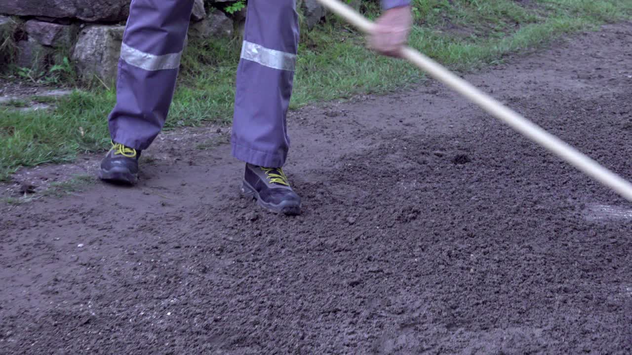 A man prepares the sandy ground with a rake during a race