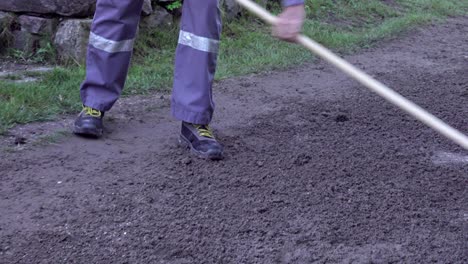 a man prepares the sandy ground with a rake during a race