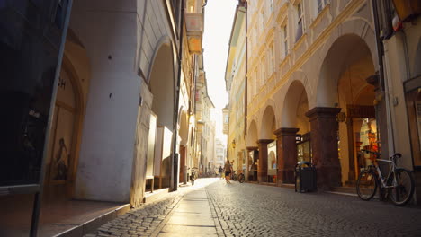 quaint cobblestone street with arched doorways backlit in bolzano, italy