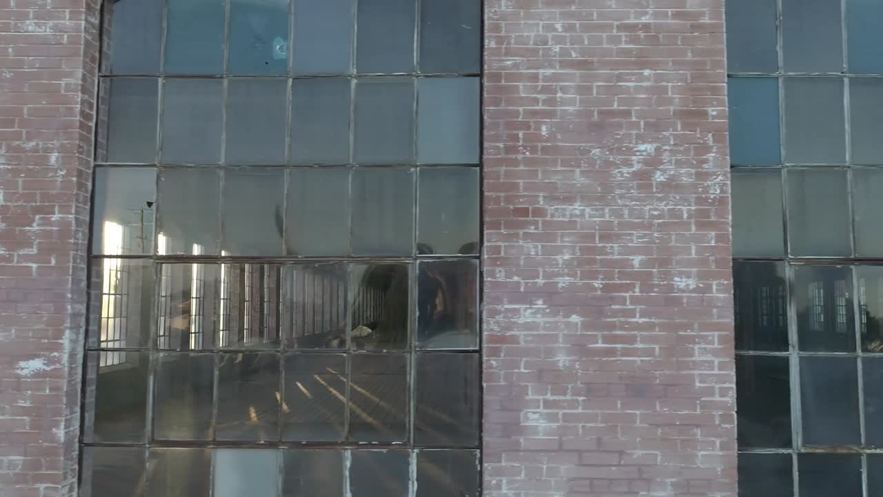 panorámica por las viejas ventanas de un edificio de ladrillo abandonado que solía ser una fábrica de algodón durante el amanecer en mckinney texas